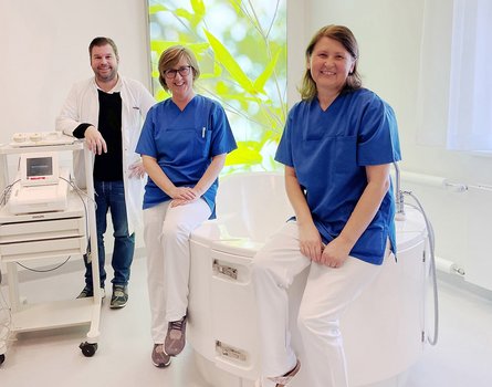Drei Personen zwei Frauen ein Mann lehnt an Ultraschallgerät