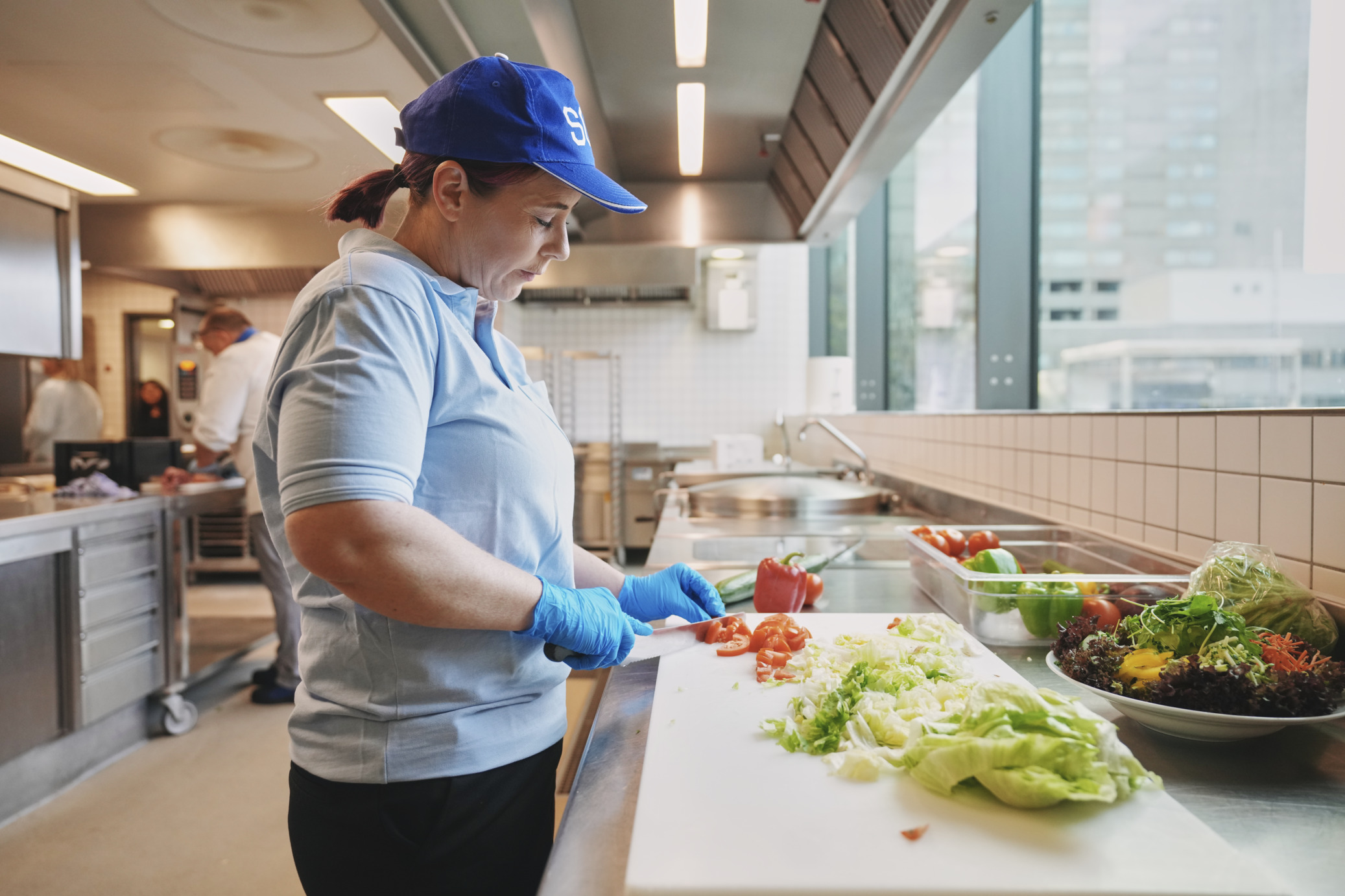 Küchenaushilfe schneidet Lebensmittel in der Krankenhausküche