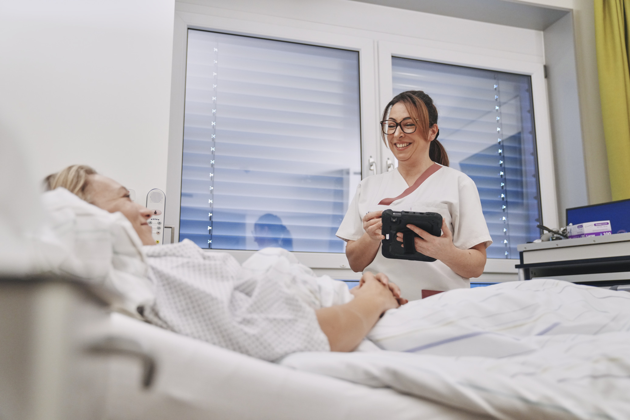 Servicekraft nimmt Essensbestellung im Patientenzimmer auf