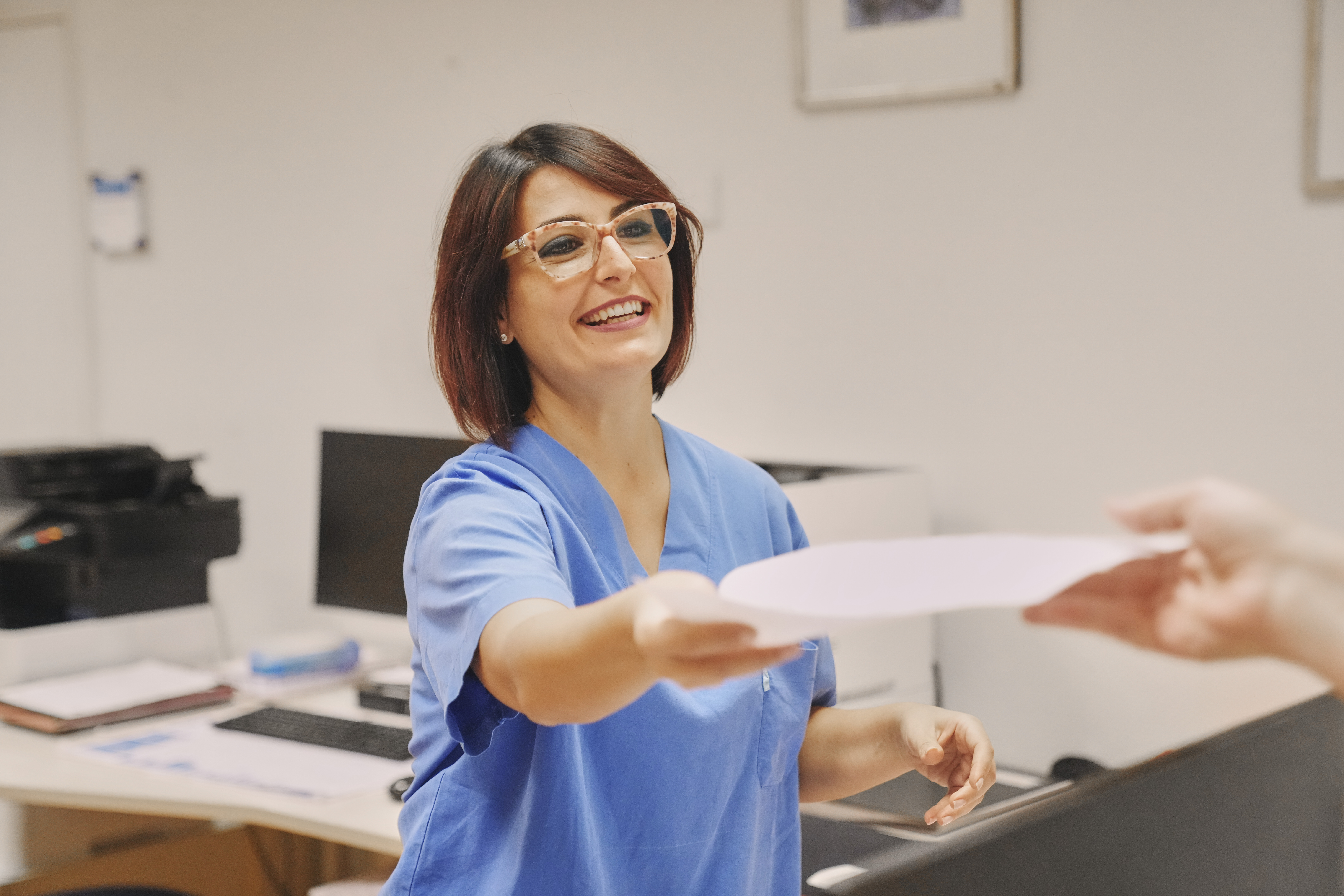 Medizinische Fachangestellte überreicht Patientendokumente an Patient