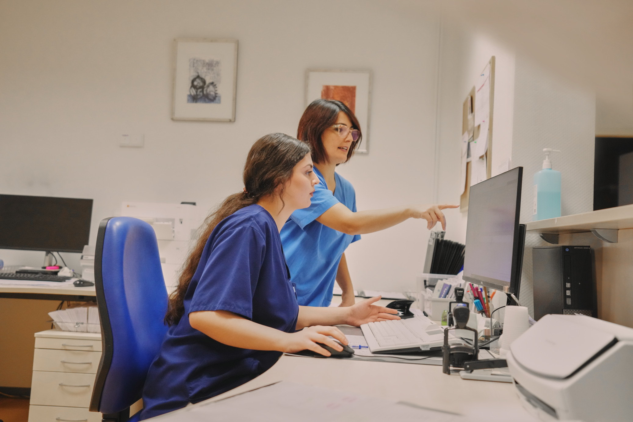 Ausbilderin erklärt einer Auszubildenen am PC Vorgehensweise