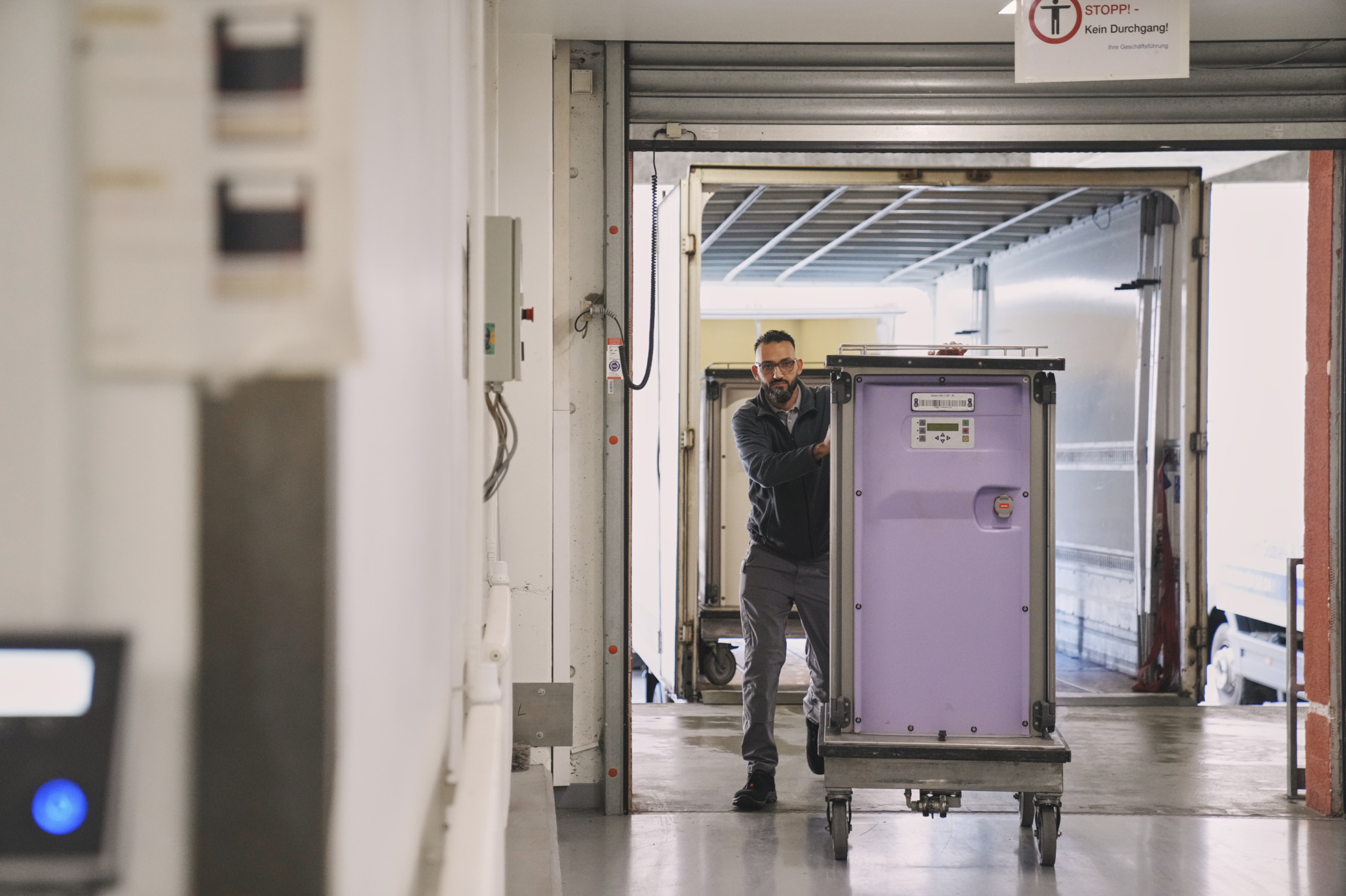 Logistik Mitarbeiter transportiert Materialcontainer