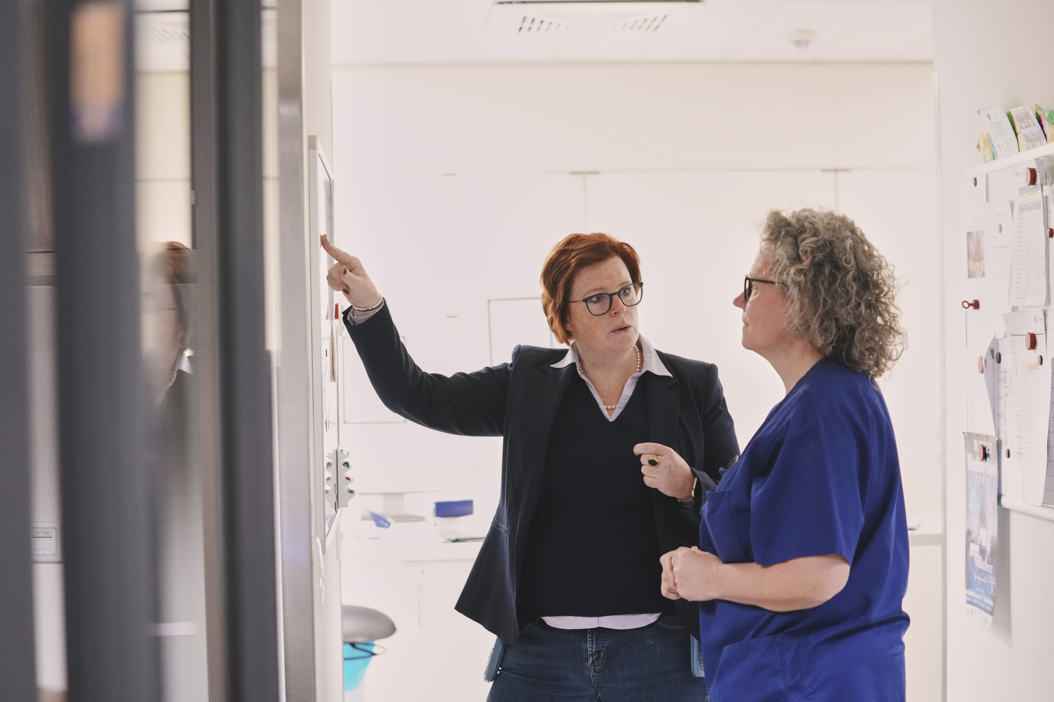 Managerin und Pflegekraft besprechen sich am Whiteboard