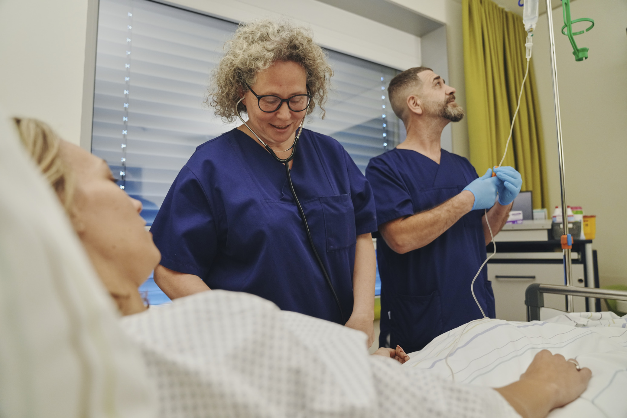 Pflegefachkräfte legen Infusion bei einer Patienten im Bett