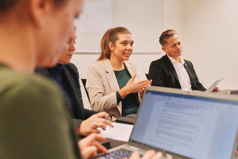Das Bild zeigt mehrere Mitarbeiter während eines Meetings.