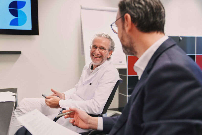 Das Bild zeigt einen Arbeit im Gespräch mit einem Kollegen.