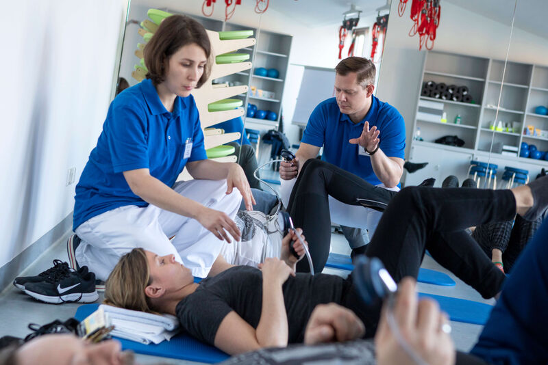 Das Bild zeigt eine Mitarbeiterin und einen Mitarbeiter bei der Behandlung von Patienten.