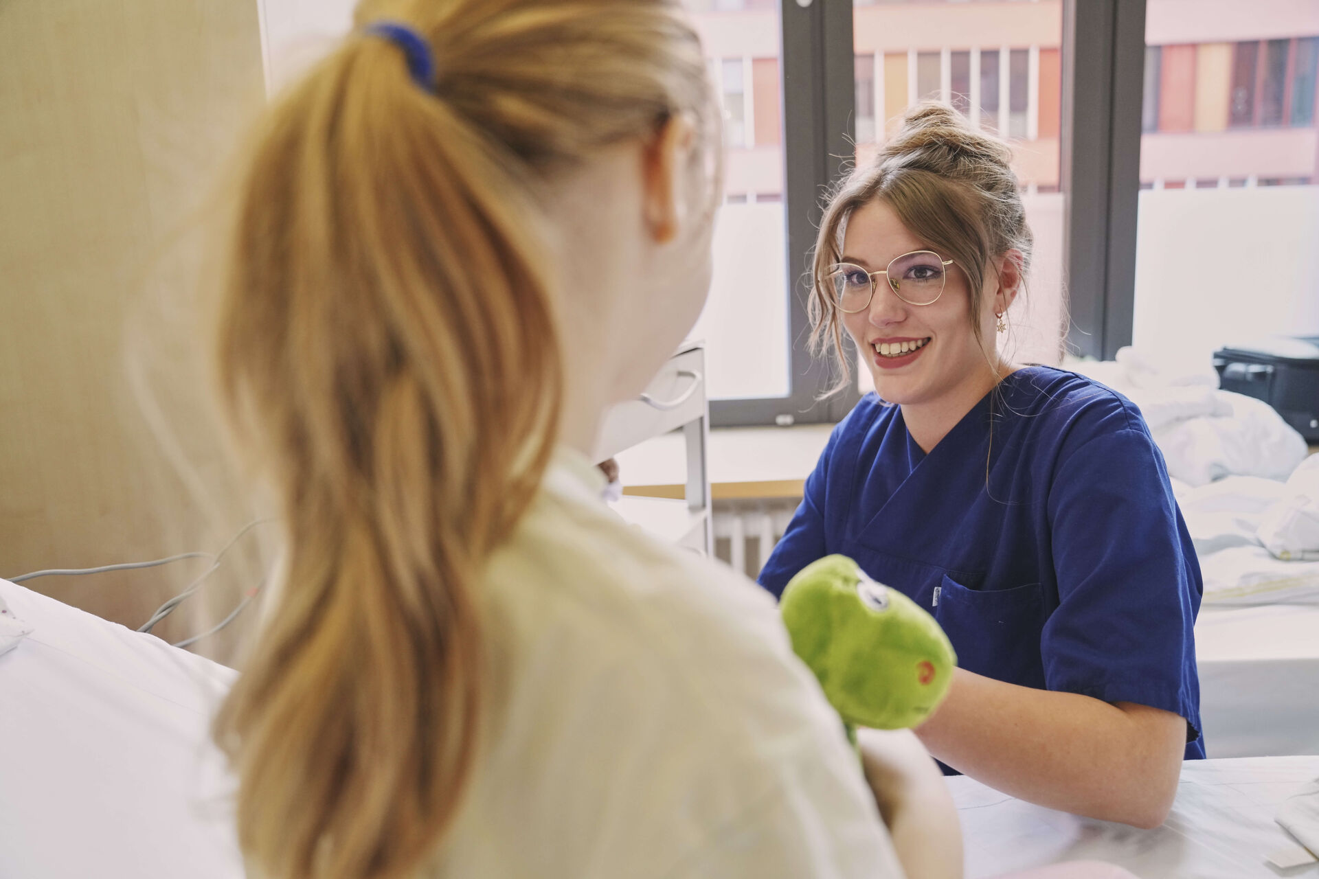 Das Bild zeigt eine Mitarbeiterin im Gespräch mit einer Patientin.