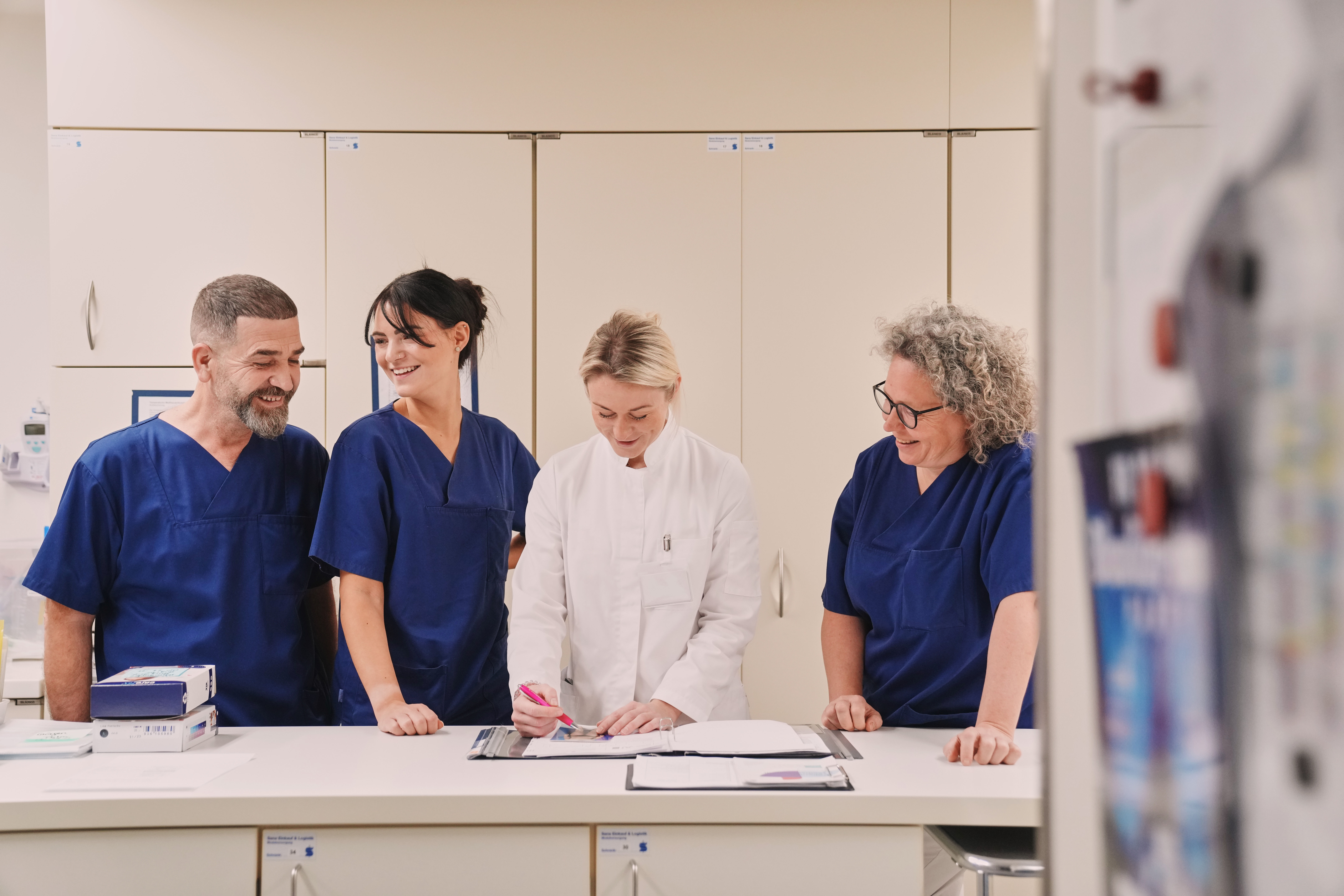 Medizinisches Team aus drei Pflegekräften und einer Ärztin am Arbeitsplatz