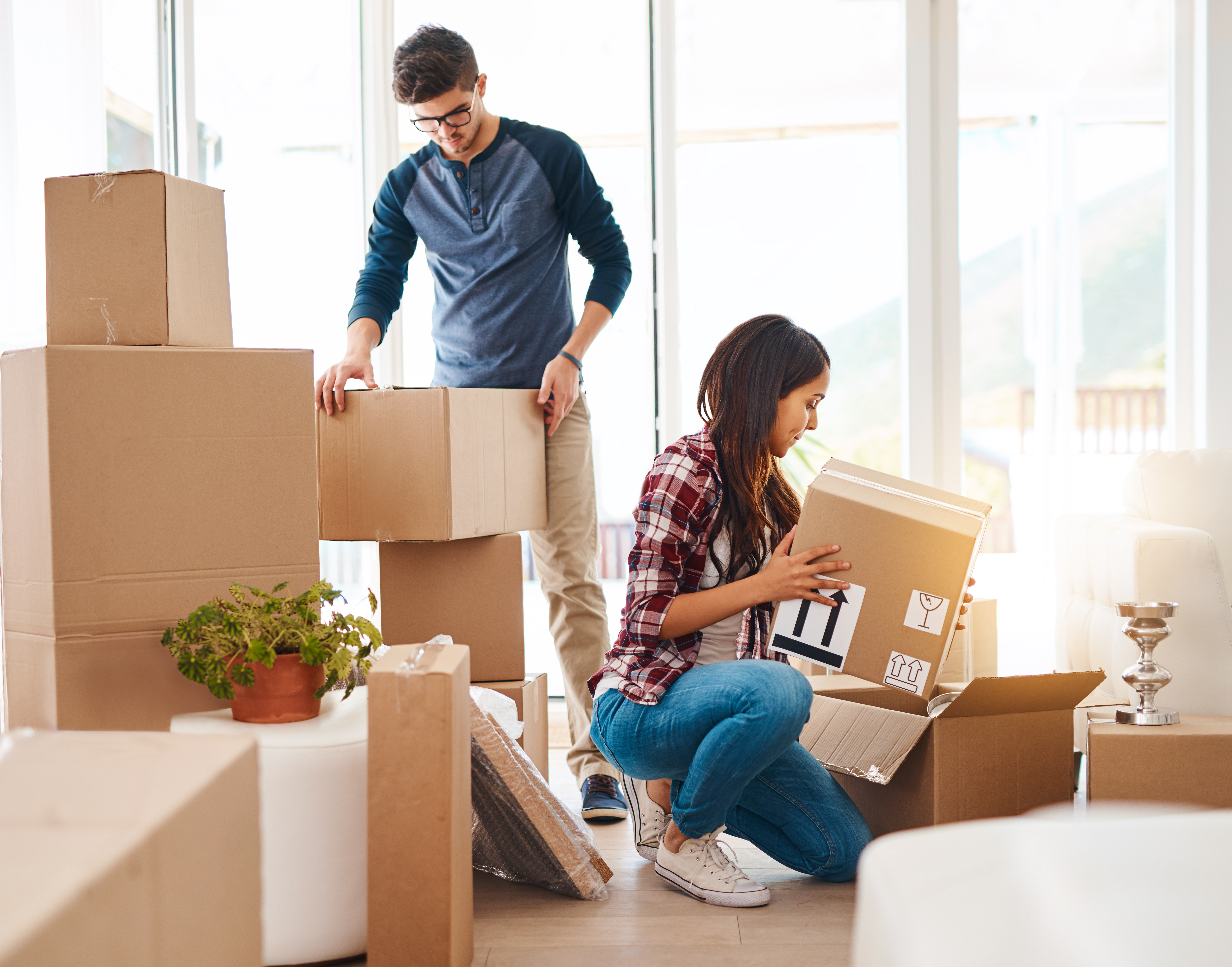Mann und Frau tragen Kartons in eine neue Wohnung.