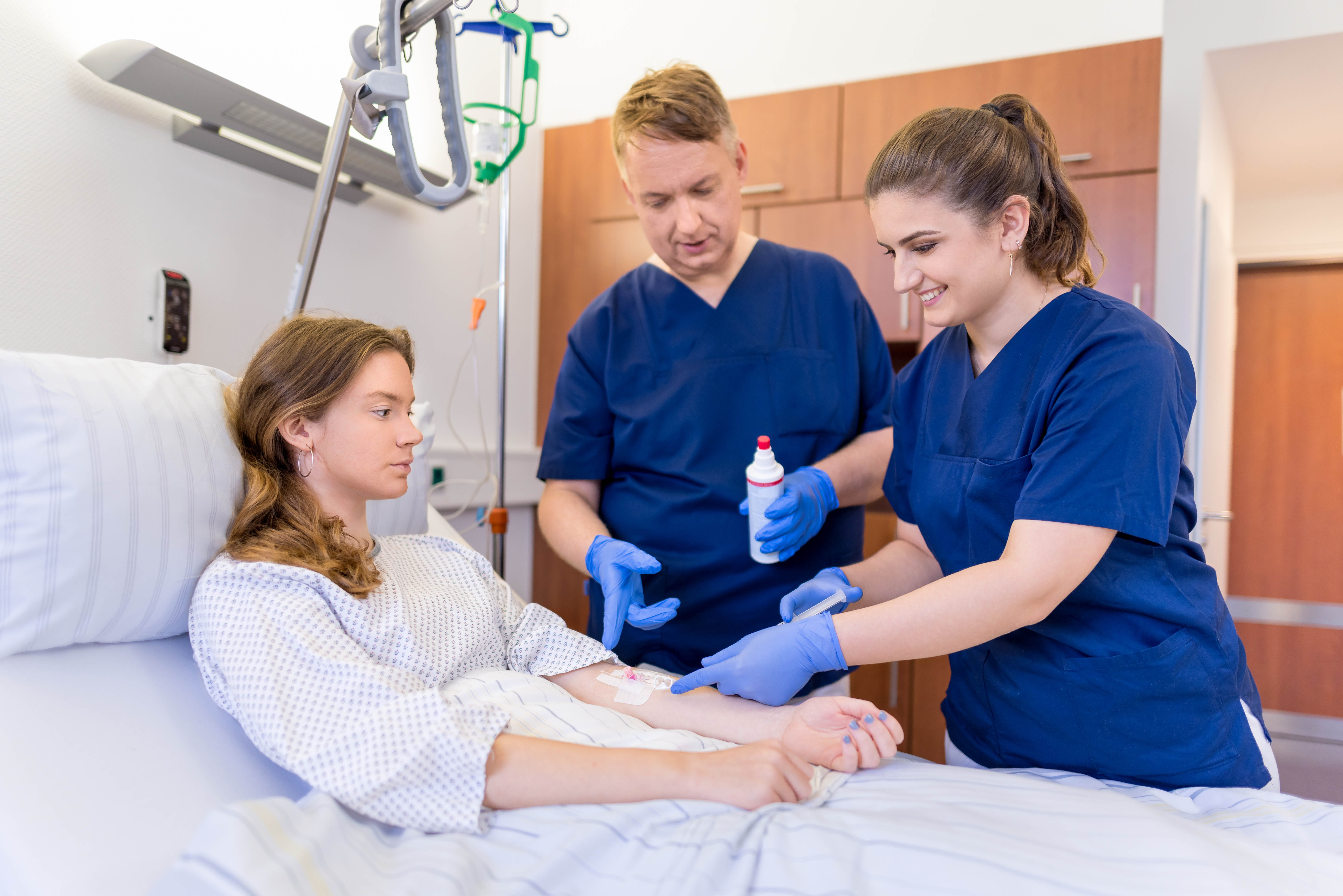 wei Pflegekräfte versorgen einen Patienten im Krankenhausbett und verabreichen ihm eine Injektion.