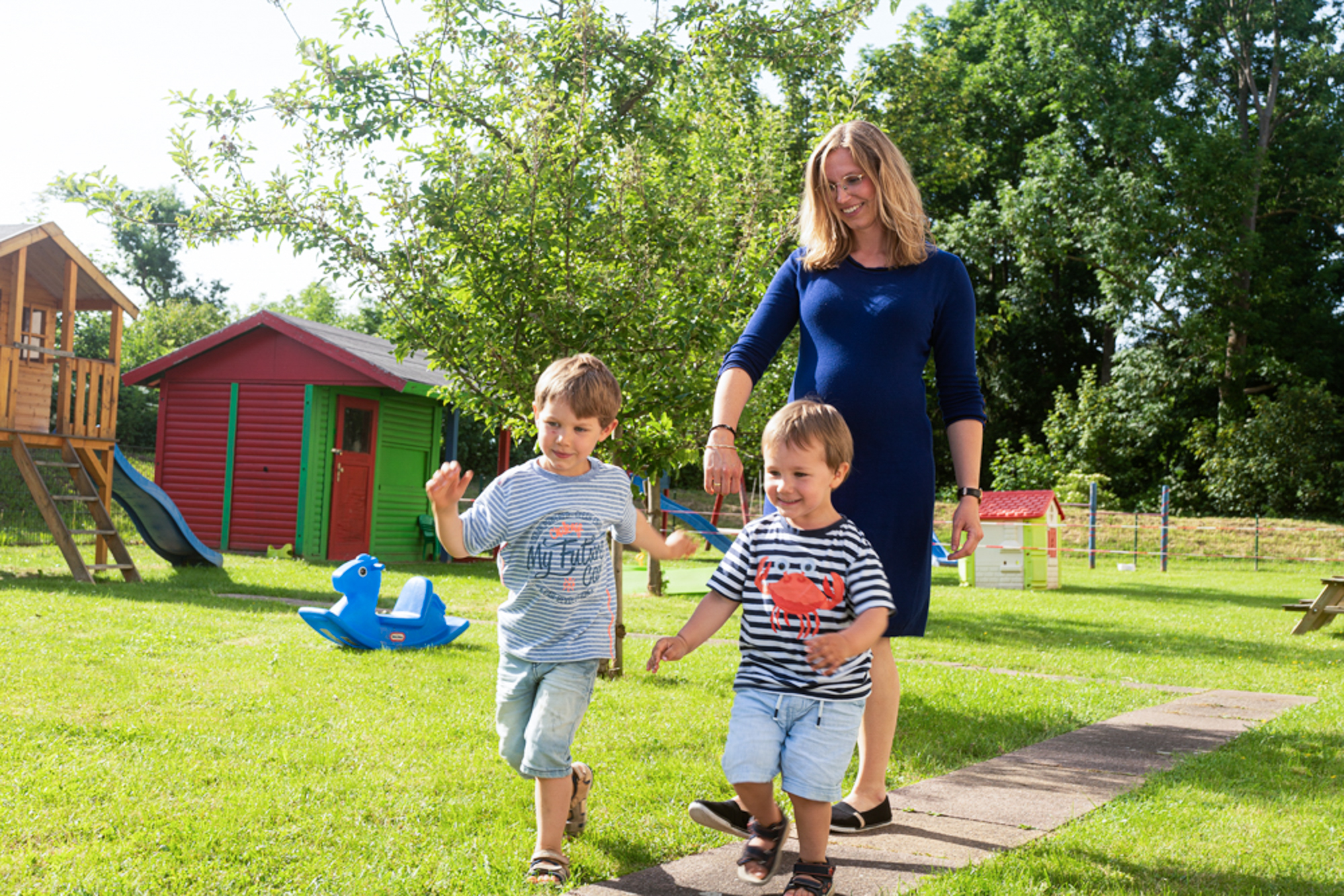 Schwangere Mutter spielt im garten mit ihren beiden Söhnen