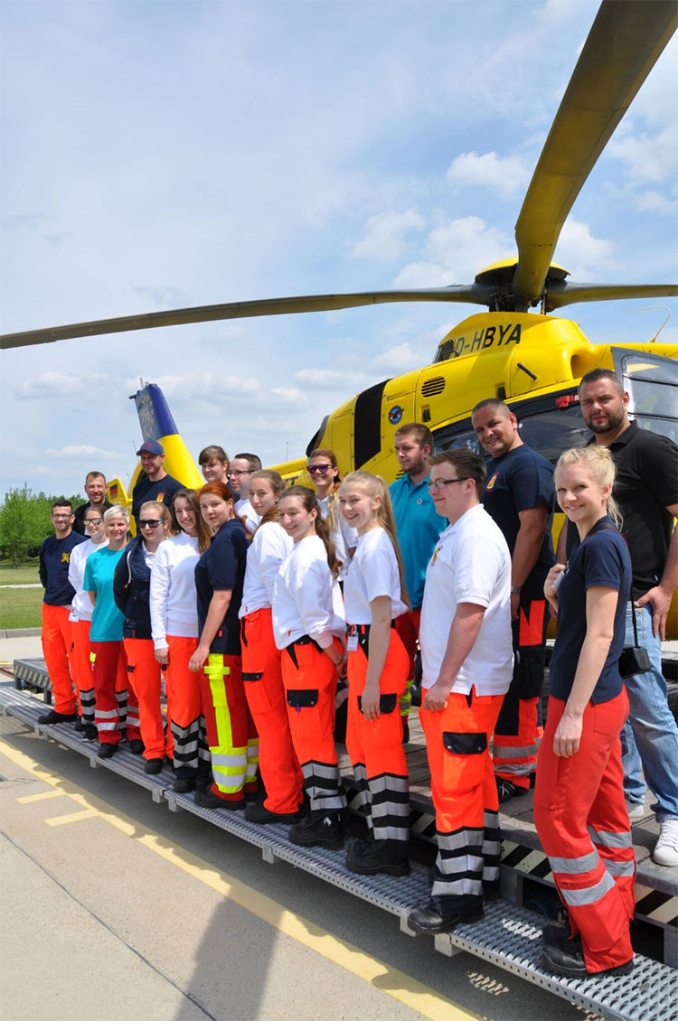 Gruppenbild von Rettungssanitätern Mit Hubschrauber im Hintergrund
