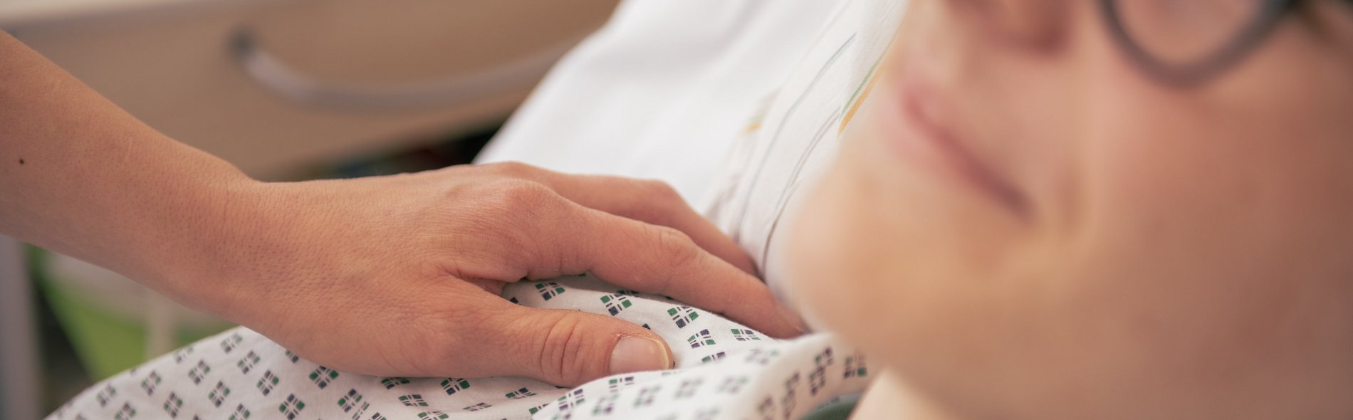 Symbolbild Zuweiser: Detailaufnahme einer tröstende Hand auf der Sculter eines Patienten im Sana Klinikum Borna 