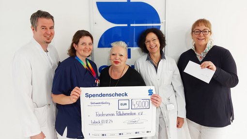 Foto von Dr. med. Merwe Carstens, Anke Junck-Dughetti, Annett Kloock und Dr. med. Tom Schmid, die stellvertretend für den Förderverein mit dem Spendenscheck überrascht wurden.