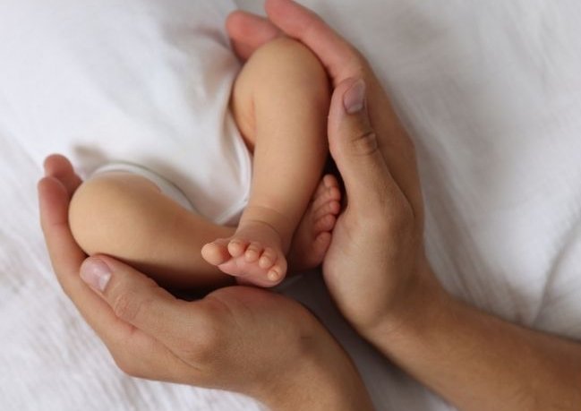 Babyfüße in den Händen der Mutter Tag der Geburt
