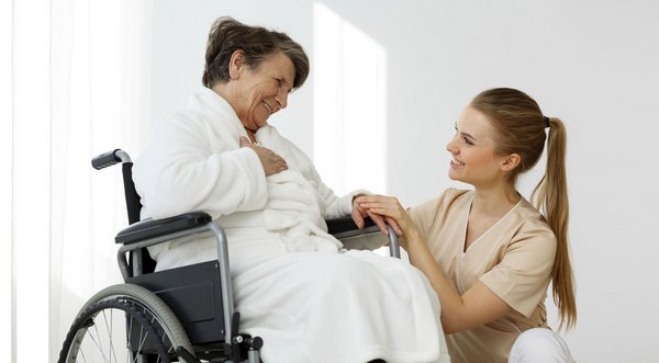 Patientin im Rollstuhl und Pflegerin