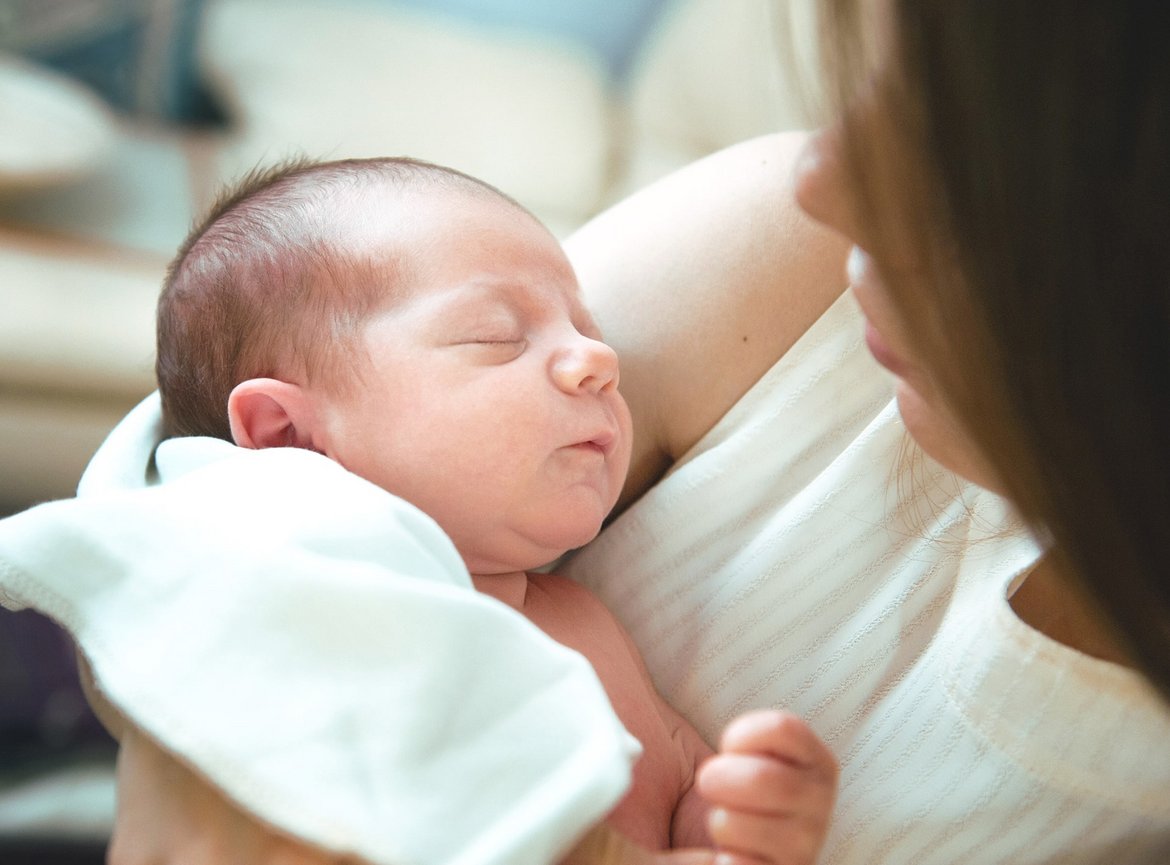 Baby mit geschlossenen Augen auf dem Arm einer Frau