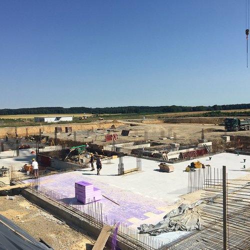 Blick von oben auf die Baustelle. Die ersten Wände stehen und die Bodenplatte ist zu sehen.