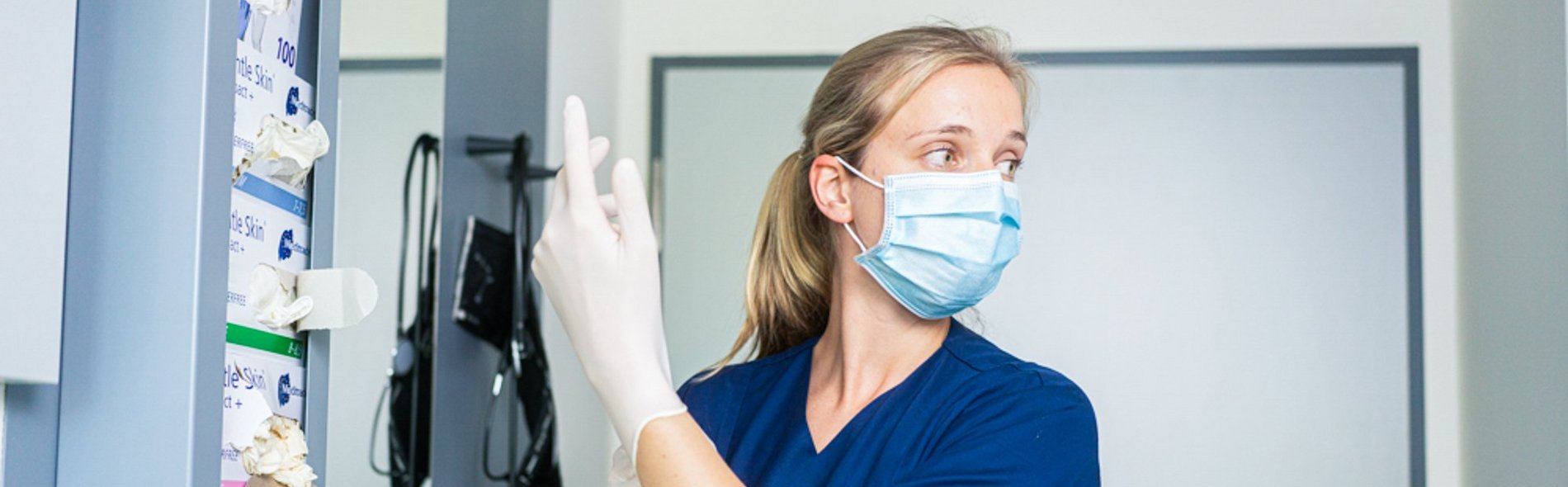 Foto einer Pflegekraft, die sich Gummihandschuhe anzieht. 