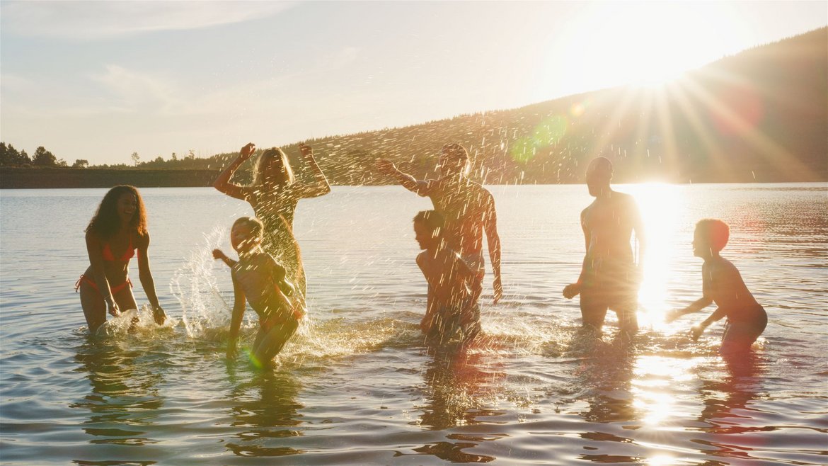 Kinder und Erwachsene planschen im flachen Wasser