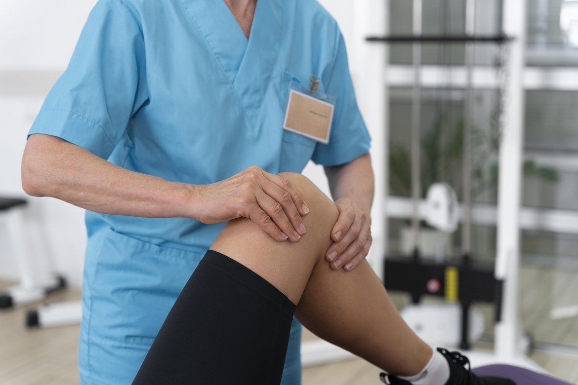 Eine Physiotherapeutin zeigt einer Patientin Übungen zur Behandlung von Knieschmerzen