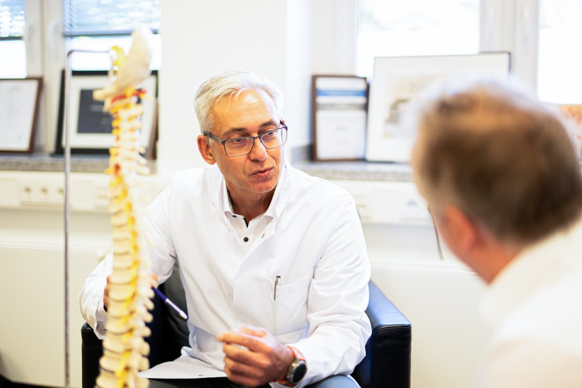 Doctor explains to patients medical treatment on the spine using a model