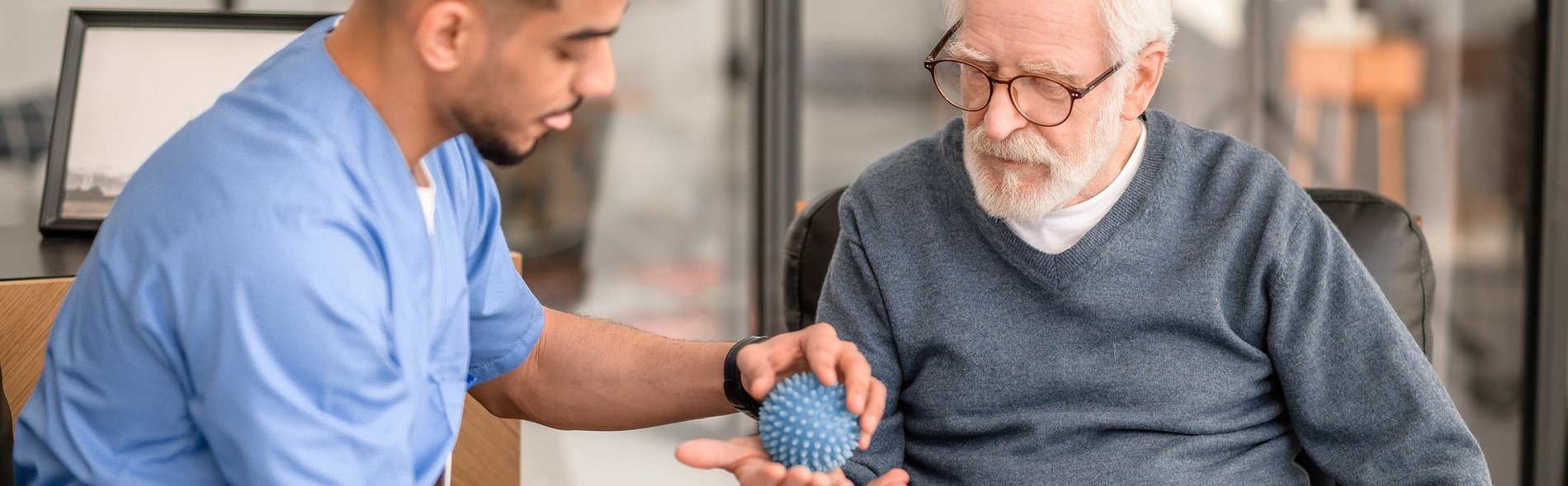 Pfleger behandelt älteren Palliativpatienten mit Massageball