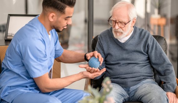 Pfleger behandelt älteren Palliativpatienten mit Massageball