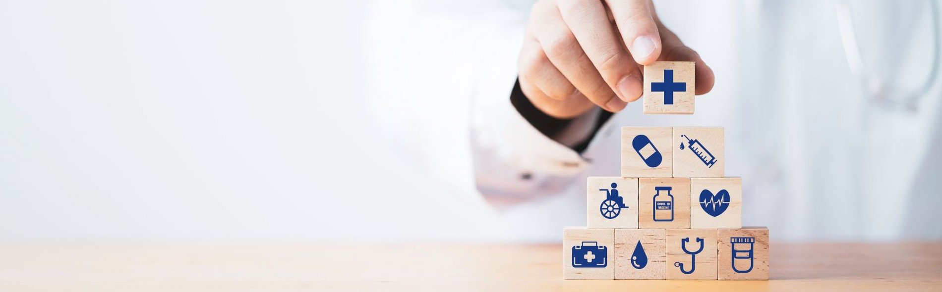 Ein Arzt stapelt Holzwürfel mit unterschiedlichen medizinischen Icons