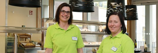 Zwei Frauen in grünem Shirt stehen im Bistro