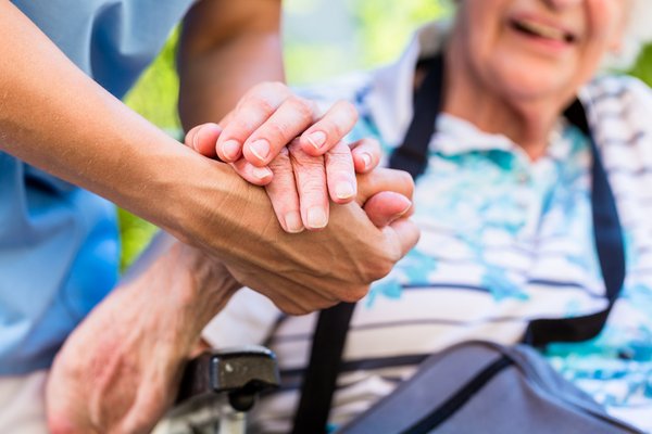 Pfleger hält Hand von alter Frau