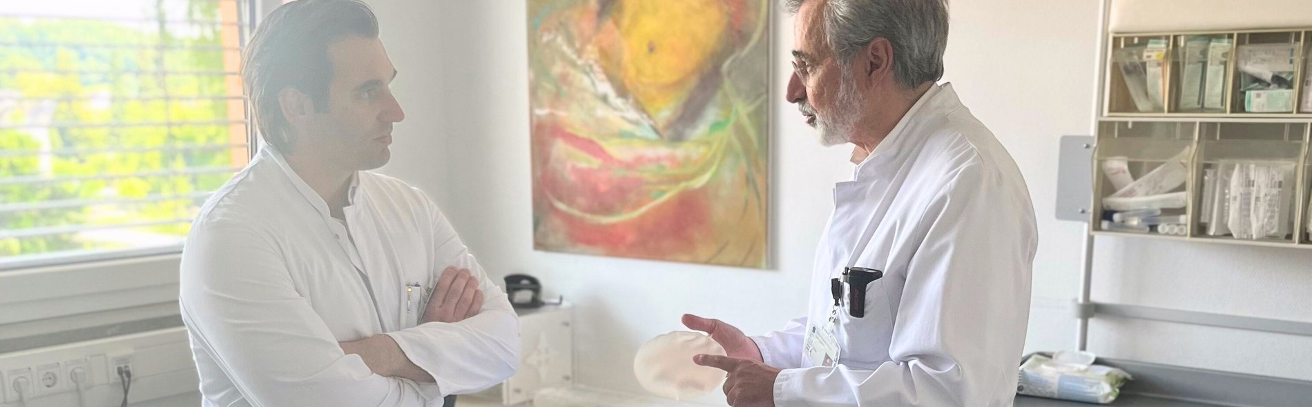 Bild zeigt Dr. med. Robert Jonathan Musmann mit Dr. med. Björn-Wieland Lisboa, welcher ein Implantat in der Hand hält