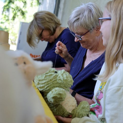 Frauen helfen in der Plüschtier-Geburtsstation beim Fertigen der Kuscheltiere.