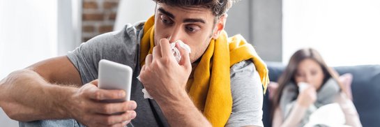 Mann mit verstopfter Nase und Smartphone