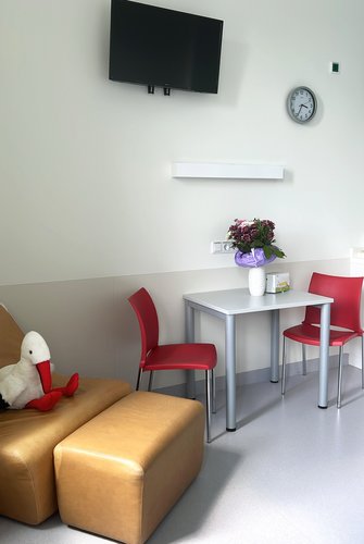 Patientenzimmer im Geburtszentrum Biberach mit Stillsessel, Tisch und Stühlen sowie Fernseher