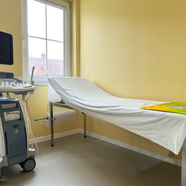 Ultraschallzimmer mit Ultraschallgerät und Liege für Patienten.