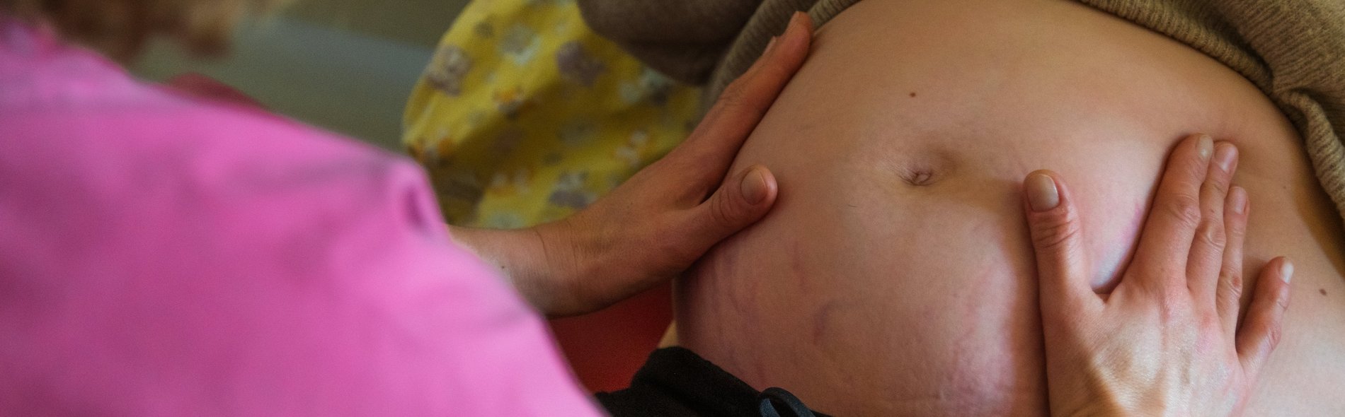 Bildausschnitt: Hebamme tastet den Bauch einer schwangeren Frau ab. Symbolbild für den hebammengeleiteten Kreißsaal am Sana Klinikum Borna 