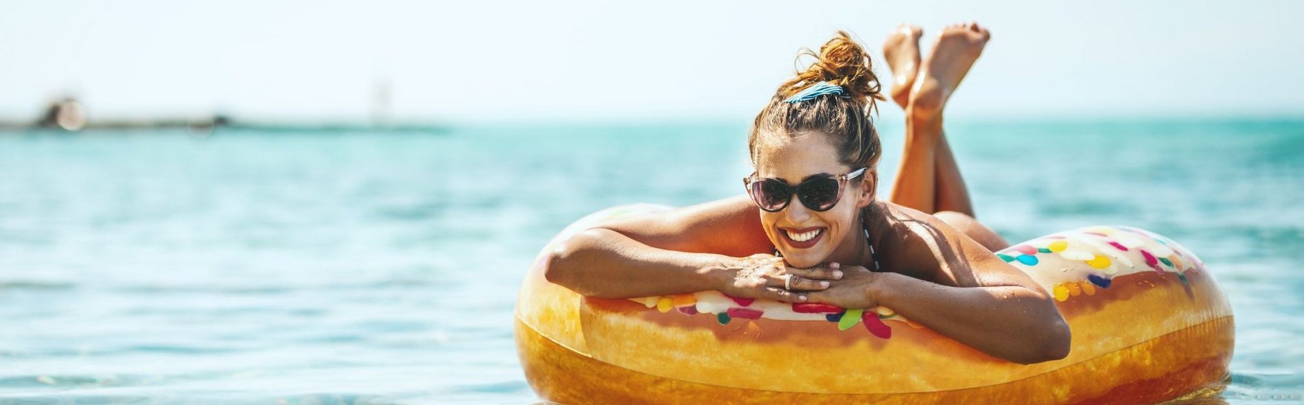 Eine Frau schwimmt mit einem Schwimmring in Form eines Donuts auf einem See.