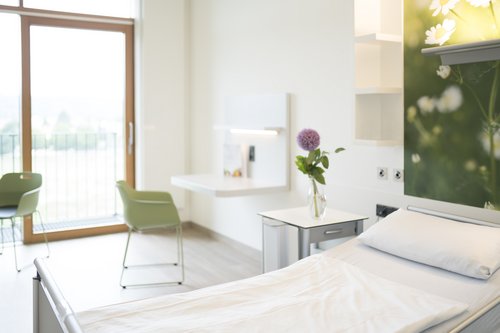 Patientenzimmer der Privatstation mit Komfortbett und großzügigem Privatbereich mit Tisch und Stühlen. 