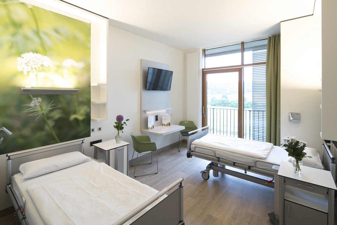 Patientenzimmer auf der Privatstation mit zwei Komfortbetten und einem geräumigen Privatbereich. 