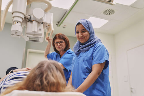 Das Bild zeigt zwei Mitarbeiterinnen während der Untersuchung einer Patientin.